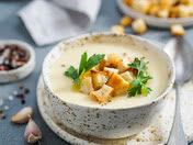 The image presents a flavorful soup in a decorative bowl, garnished with croutons and fresh parsley.