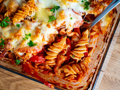 This image features a comforting pasta bake layered with rich tomato sauce, melted organic Allgäu cheese, and fresh herbs.