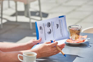 The image shows one of our Allgäu cheesemakers reviewing production notes while enjoying a cup of fair-trade coffee and a glass of organic herbal tea.