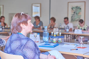 The image depicts a group of people gathered in a conference room for a meeting or discussion.