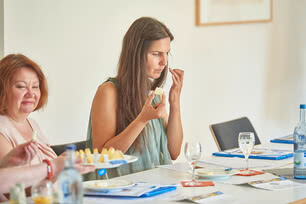 The image shows several guests sitting at a table, taking part in a guided tasting of our Allgäu organic cheeses.