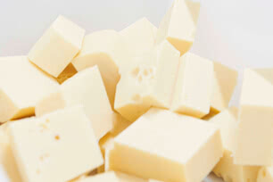 The image presents several square pieces of white or pale-coloured cheese.
