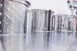 The image displays several metal containers featuring perforated sides.