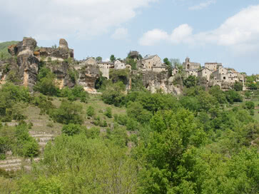The image depicts a small, historic settlement nestled on a rocky cliff, surrounded by lush green vegetation—a scene that echoes the natural setting where our Allgäu region cheeses are crafted.