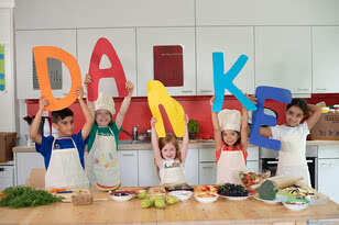 The image depicts children holding large letters to spell out
