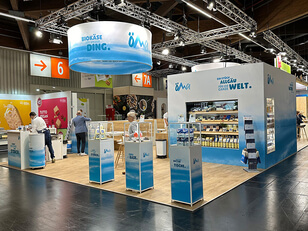 The image features our trade-fair stand, where we showcase certified organic cheese specialities from the Allgäu region.