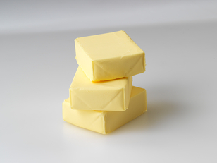 The image displays three individual portions of organic butter, neatly stacked.