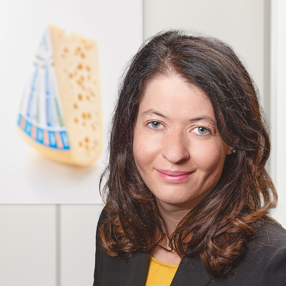 The image presents a woman set against a backdrop that includes a piece of cheese.